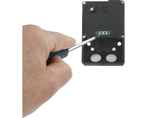 Eine Person benutzt einen Schraubendreher, um eine elektrische Verbindung herzustellen.