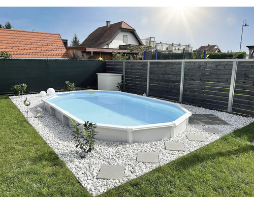 Ovaler Pool im Garten mit weißem Kies und Steinplatten