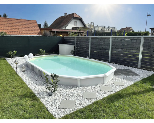 Ein Aufstellpool im Garten, umgeben von weißen Steinen und Rasen