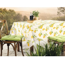 Gedeckter Tisch mit Zitronenmuster-Tischdecke und Stühlen im Freien.