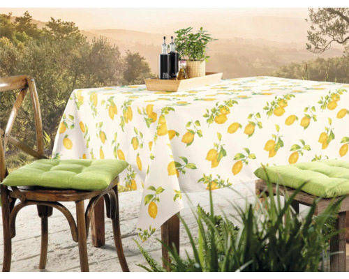 Gedeckter Tisch mit Zitronenmuster-Tischdecke und Stühlen im Freien.