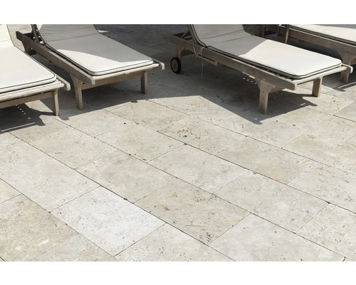 Terrasse mit Travertin Pflastersteinen und Liegestühlen aus Holz.