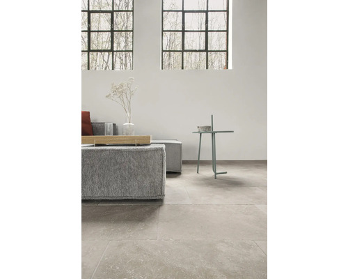 Wohnzimmer mit grauem Sofa, Beistelltisch und Natursteinboden.