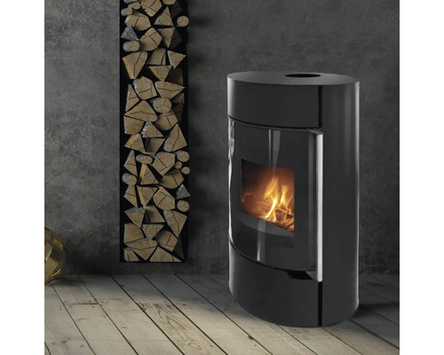 Schwarzer Kaminofen neben einem Regal mit Holzscheiten in einem hellen Raum