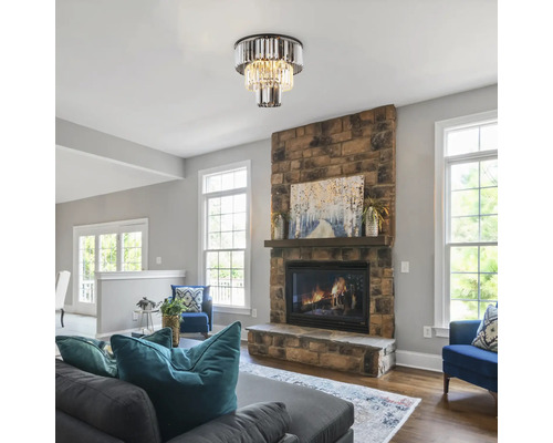 Wohnzimmer mit Deckenleuchte im Kristallstil über einem Steinkamin