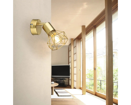 Goldfarbene Wandleuchte mit geometrischem Lampenschirm im Wohnzimmer.