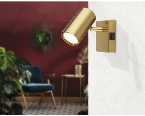 Goldene Wandleuchte mit Schalter in einem Wohnzimmer