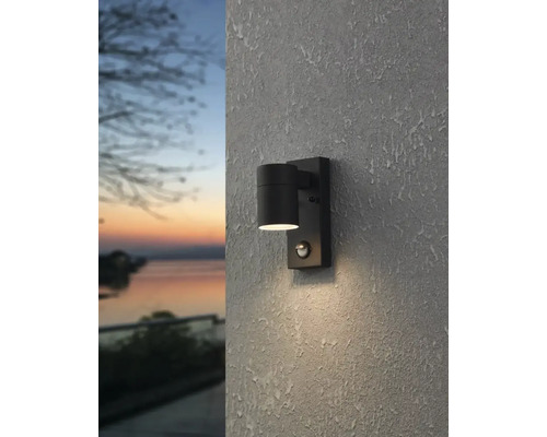 Schwarze Außenwandleuchte mit Bewegungsmelder an einer strukturierten Wand