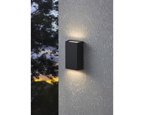 Schwarze Außenwandleuchte beleuchtet eine Wand