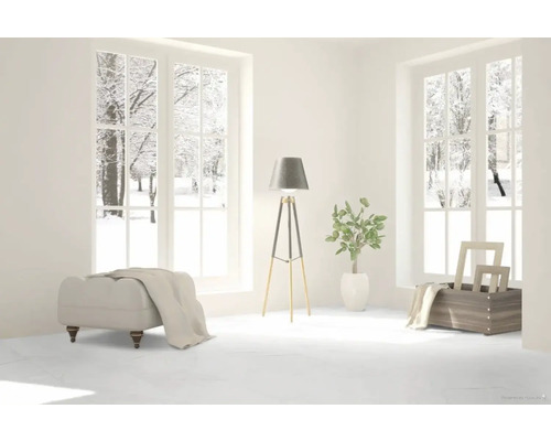 Heller Raum mit Fensterblick auf verschneite Bäume, Hocker, Stehlampe und Dekoration