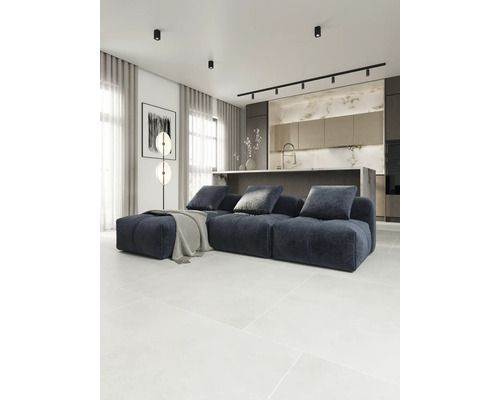 Wohnzimmer mit modularem Sofa, Stehleuchte und offener Küche.