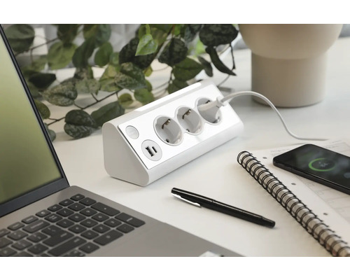 Steckdosenleiste mit USB-Anschlüssen auf einem Schreibtisch mit Laptop und Smartphone