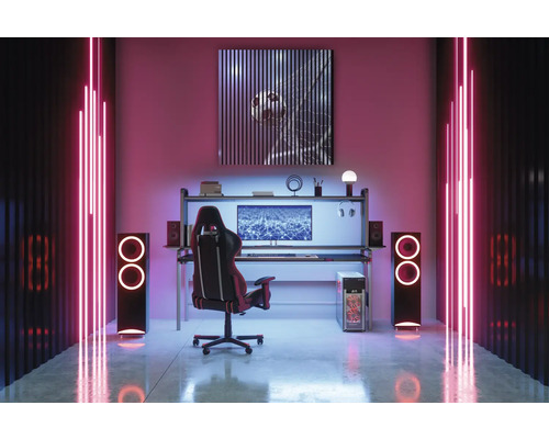 Ein Gamingzimmer mit Schreibtisch, Stuhl, Lautsprechern und Neonbeleuchtung.