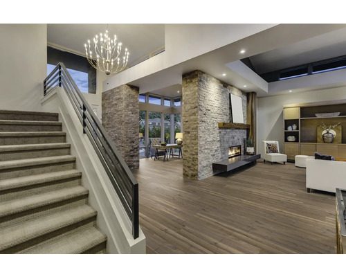 Innenaufnahme eines Wohnzimmers mit Treppe, Kamin, Holzfußboden und Beleuchtung