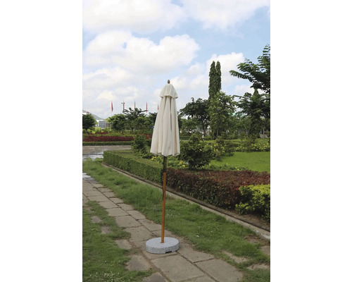 Geschlossener Sonnenschirm mit Ständer in einem Garten.