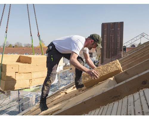 Ein Arbeiter verlegt Dämmmaterial auf einem Dach.