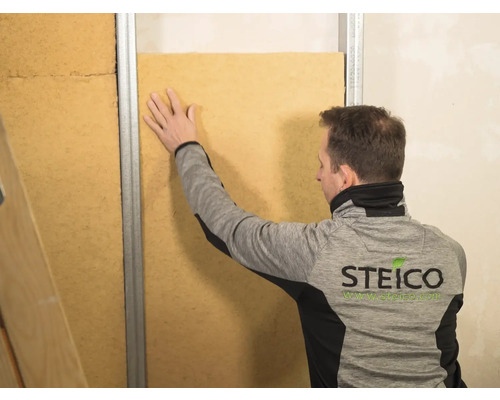 Mann montiert Holzfaserdämmplatte an Wandkonstruktion