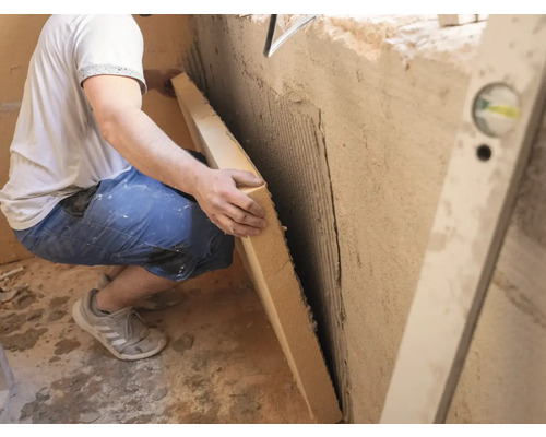 Handwerker montiert Dämmplatte an Wand