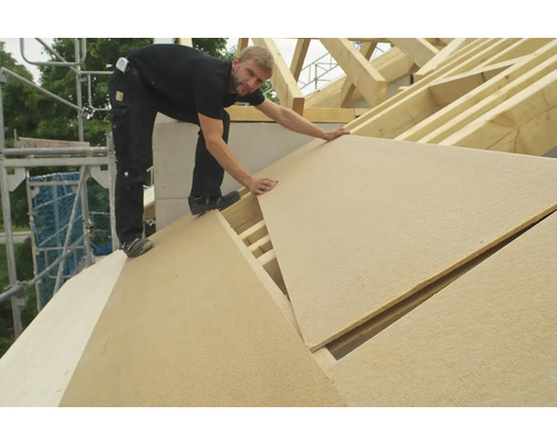 Handwerker verlegt Holzfaserplatten auf einem Dach
