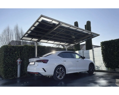 Ein Carport aus Metall und Glas schützt ein Auto vor Witterungseinflüssen.