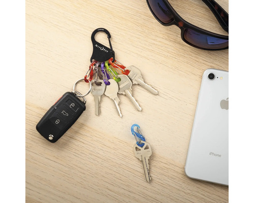 Schlüsselanhänger mit Schlüssel, Autoschlüssel, Karabinerhaken und Smartphone auf einem Tisch