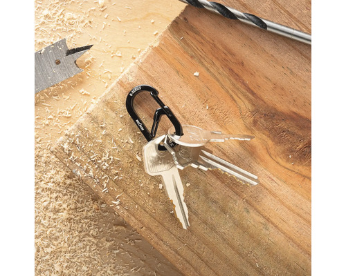 Schlüsselanhänger mit Schlüsseln auf einem Holzbrett neben Bohrern