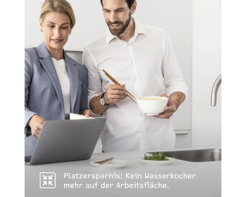 Zwei Personen in einer Küche. Eine Frau mit Laptop und ein Mann mit einer Schüssel und Essstäbchen.