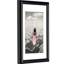 Gerahmtes Wandbild mit Frau auf Schaukel vor Stadtkulisse