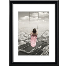 Gerahmtes Bild mit dem Motiv eines Mädchens auf einer Schaukel über einer Stadt