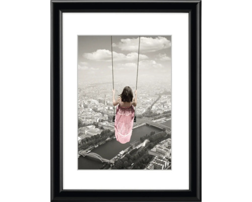 Gerahmtes Bild mit dem Motiv eines Mädchens auf einer Schaukel über einer Stadt