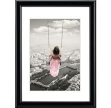 Gerahmtes Bild mit einer Frau auf einer Schaukel über einer Stadt