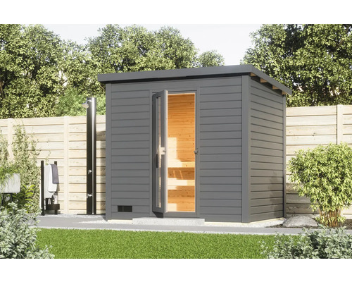 Saunahaus Karibu Talos 3 inkl. 9 KW Ofen u.integr.Steuerung und Holztür und Isolierglas terragrau Garten Szene mit einer grauen Außensauna mit geöffneten Glastüren und einer Außendusche.