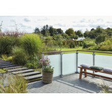 Terrasse mit Sichtschutzwand aus Glas, Bank und Bepflanzung in einem Garten.