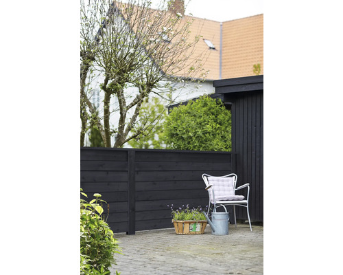 Gartenszene mit Holzzaun, Gartenstuhl, Gießkanne und Pflanzenkorb