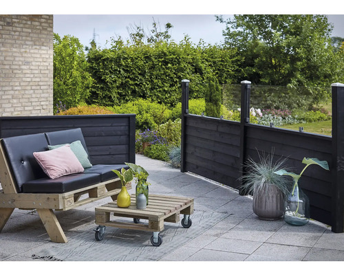 Gartenbereich mit Holzterrasse, Palettenmöbeln und Sichtschutzzaun aus Holz und Glas