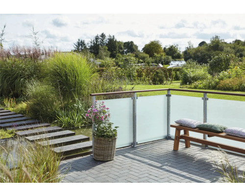 Terrasse mit Sichtschutzwand aus Glas, Bank und Bepflanzung im Garten