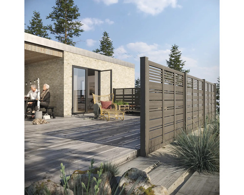 Terrasse mit Holzboden und Holzzaun, Sitzbereich und Wohnhaus im Hintergrund.